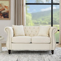 Canapé Chesterfield deux places en velours beige, accoudoirs arrondis, garniture cloutée