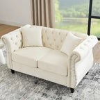 Canapé Chesterfield deux places en velours beige, accoudoirs arrondis, garniture cloutée