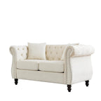 Canapé Chesterfield deux places en velours beige, accoudoirs arrondis, garniture cloutée