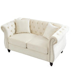 Canapé Chesterfield deux places en velours beige, accoudoirs arrondis, garniture cloutée