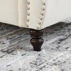 Canapé Chesterfield deux places en velours beige, accoudoirs arrondis, garniture cloutée