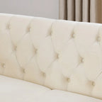Canapé Chesterfield deux places en velours beige, accoudoirs arrondis, garniture cloutée